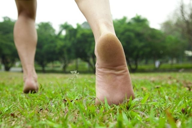 Närbild av bara fötter som går på gräs i en park